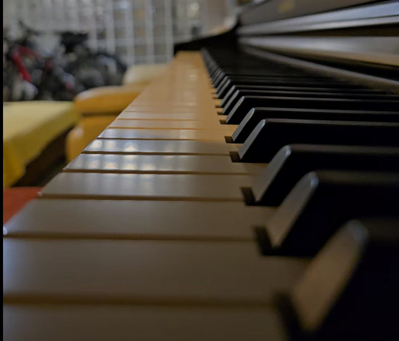 A close view along the ivory and black keys of a wooden upright piano.