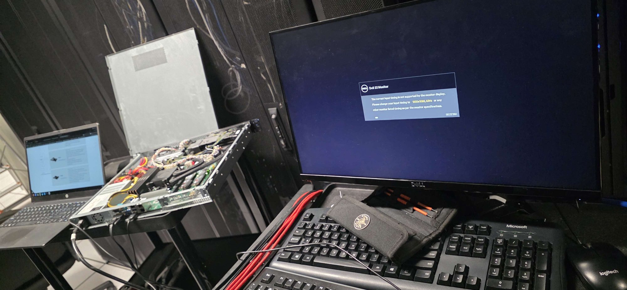 An open server beside a laptop and monitor during hardware maintenance.