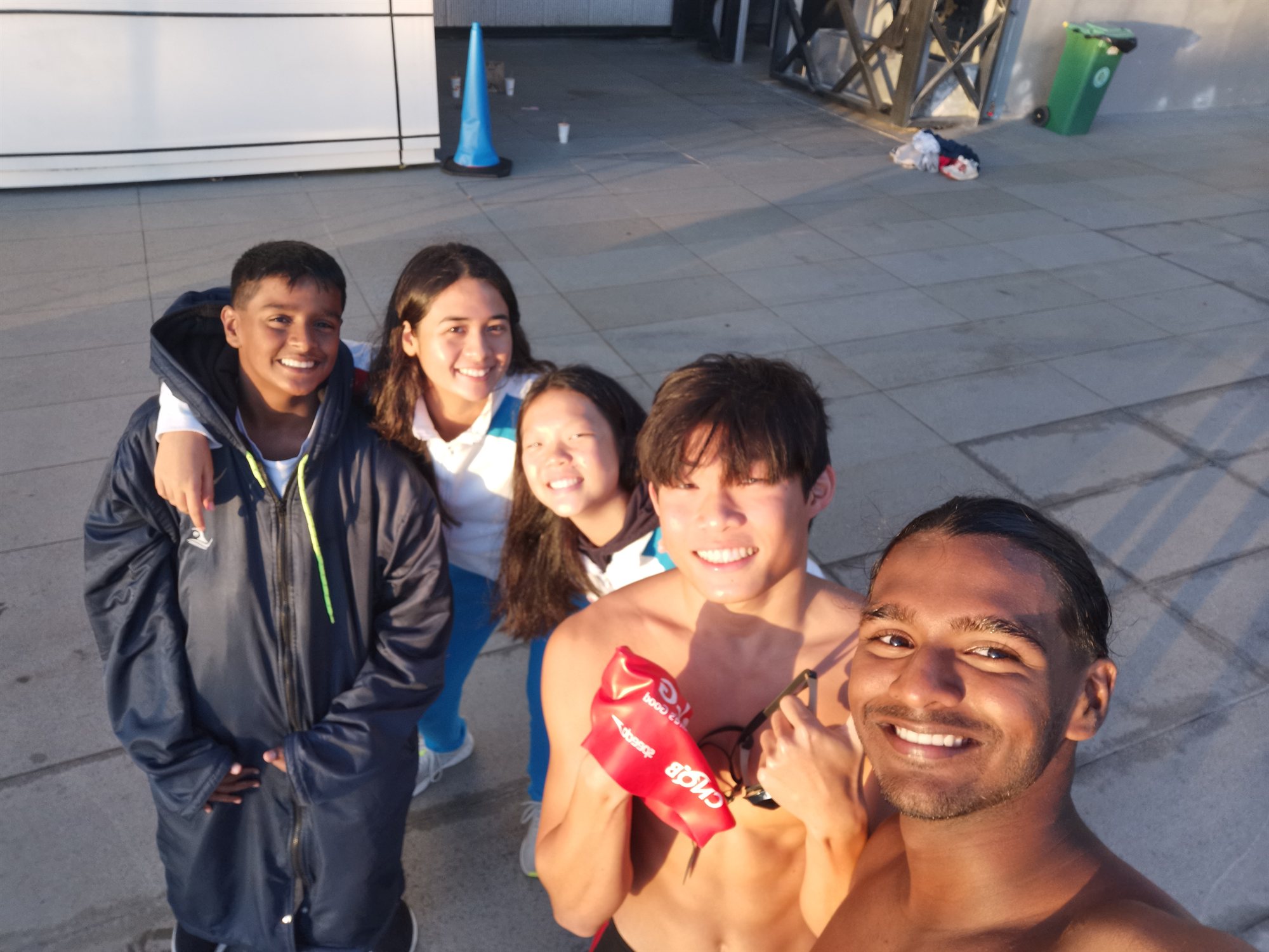 A group smiling together outside a swimming facility